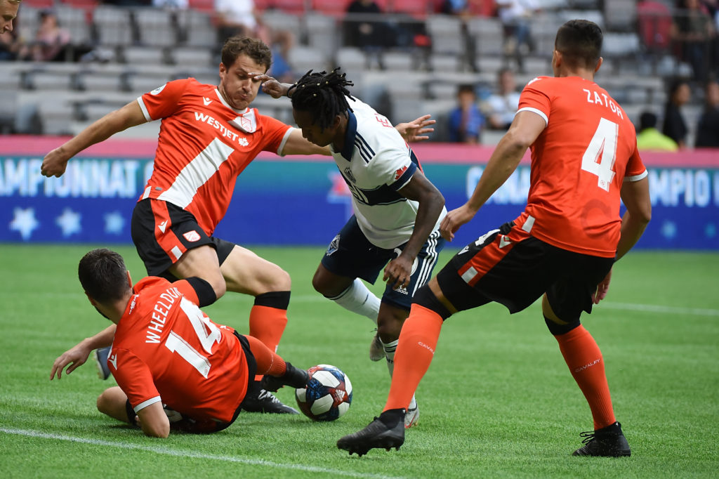 Jul 24, 2019; Vancouver, British Columbia, Canada; Vancouver Whitecaps midfielder Yordy Reyna (29) battles for the ball against Cavalry FC defender Jonathan Wheeldon (14) and defender Dominick Zator (4) during the first half at BC Place Stadium. Mandatory Credit: Anne-Marie Sorvin-USA TODAY Sports