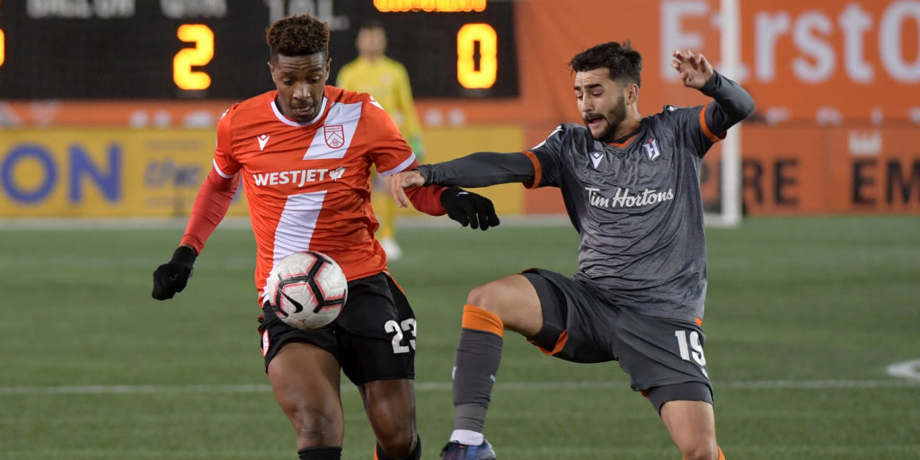 Oct 16, 2019; Hamilton, Ontario, CAN; Cavalry FC forward Dominique Malonga (23) tries to get past Forge FC midfielder Tristan Borges (19) in the second half of a Canadian Premier League soccer match at Tim Hortons Field. Mandatory Credit: Dan Hamilton-USA TODAY Sports for CPL