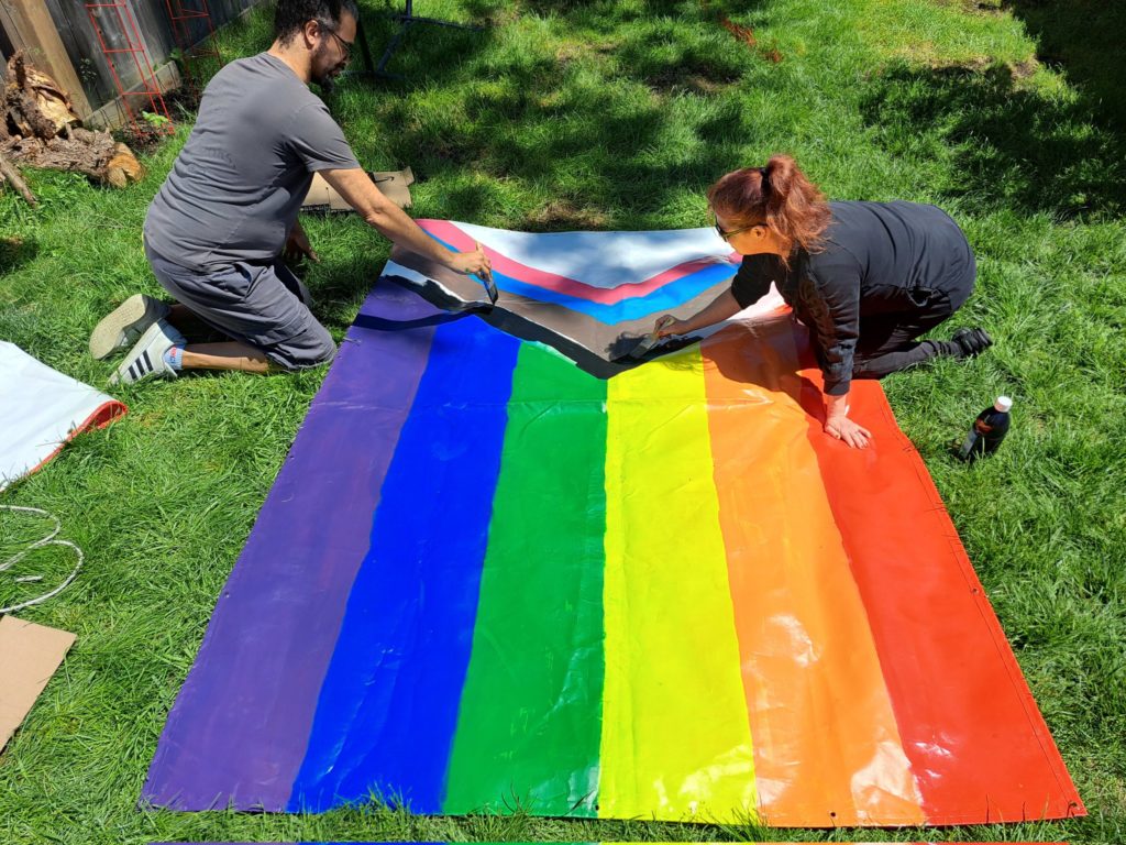 Members of Barton St. Battalion prepare a Pride flag banner.